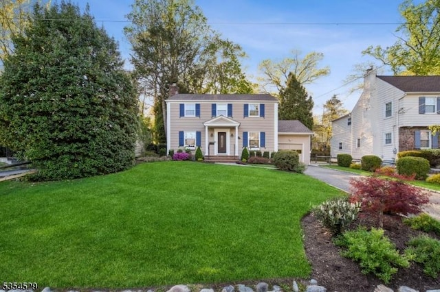 colonial home with a chimney, a front yard, and aphalt driveway