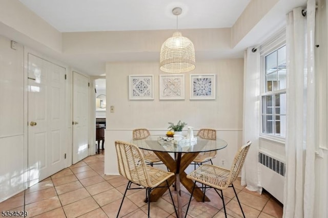 dining room featuring an inviting chandelier, radiator, and light tile patterned floors