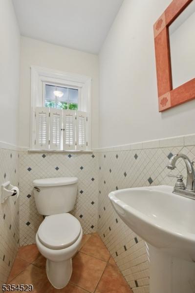 bathroom featuring toilet, tile walls, wainscoting, and tile patterned flooring