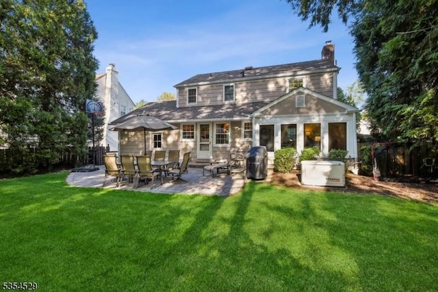 rear view of property featuring a yard, fence, a chimney, and a patio area