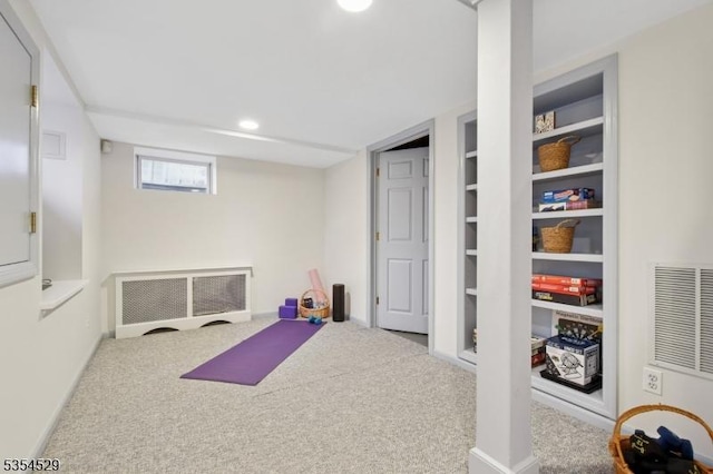 exercise area featuring radiator, carpet flooring, recessed lighting, and built in shelves