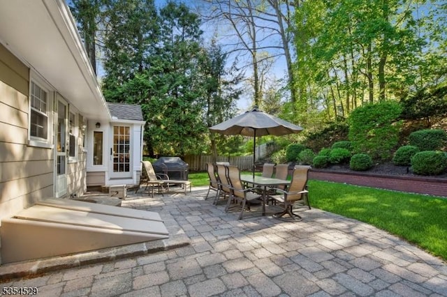 view of patio with outdoor dining area, fence, and a grill