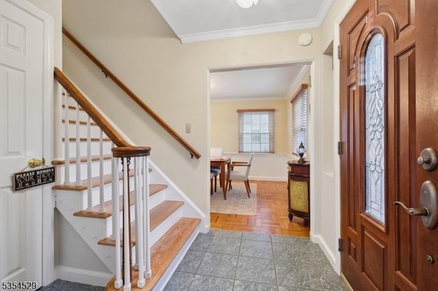 entrance foyer with crown molding, baseboards, and stairway