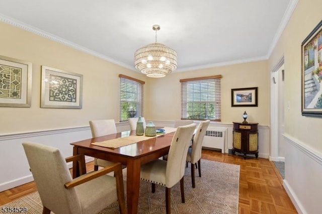 dining area featuring crown molding, radiator heating unit, a wainscoted wall, and a chandelier