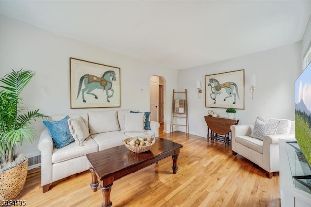 living room featuring arched walkways and light wood-type flooring