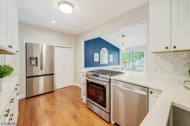 kitchen featuring appliances with stainless steel finishes, light wood finished floors, decorative backsplash, light countertops, and white cabinetry