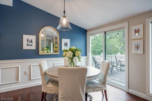dining area featuring lofted ceiling, wainscoting, and wood finished floors