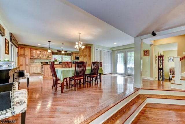 dining space featuring light wood-style floors, baseboards, recessed lighting, and a notable chandelier