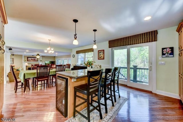 kitchen featuring an inviting chandelier, a kitchen island, a breakfast bar area, light wood-type flooring, and hanging light fixtures