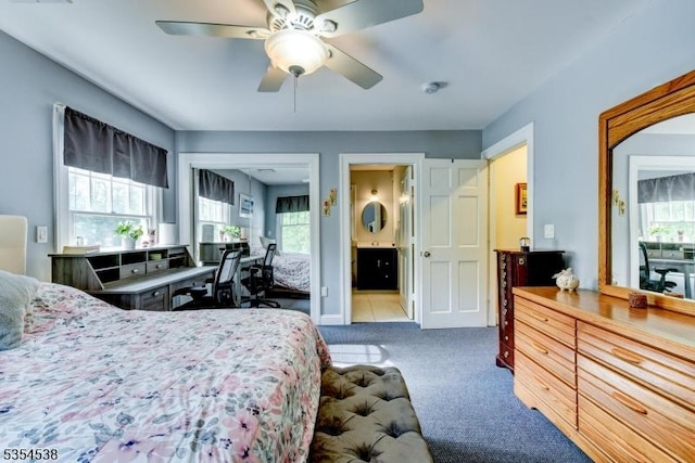 bedroom featuring carpet floors, ceiling fan, ensuite bath, and multiple windows