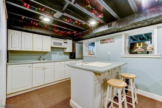 kitchen with visible vents, a sink, white cabinetry, and white microwave