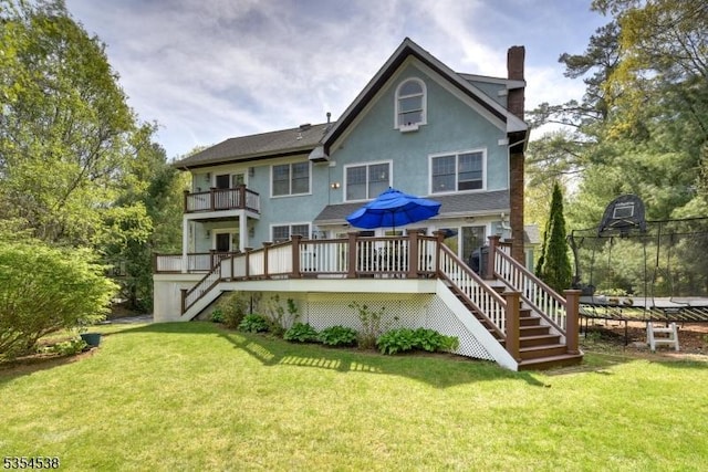 back of property with a chimney, a wooden deck, a yard, stairs, and stucco siding