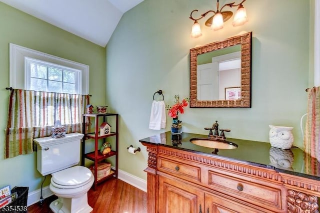 bathroom featuring vanity, wood finished floors, toilet, baseboards, and vaulted ceiling