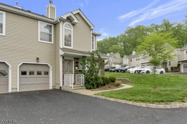 view of side of home featuring a chimney, a garage, a yard, driveway, and a residential view