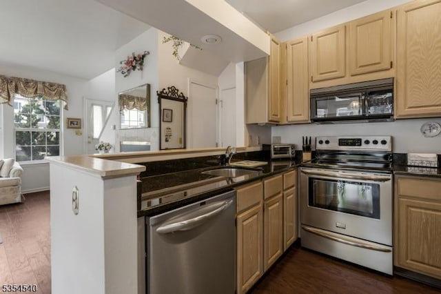 kitchen featuring stainless steel appliances, a peninsula, a sink, dark wood-style flooring, and vaulted ceiling