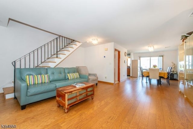living area with light wood-style floors, stairs, baseboards, and visible vents