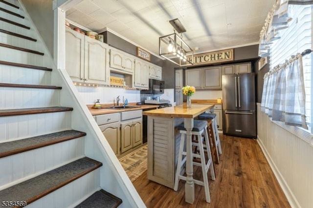 kitchen featuring a center island, a sink, freestanding refrigerator, dark wood-style floors, and butcher block counters