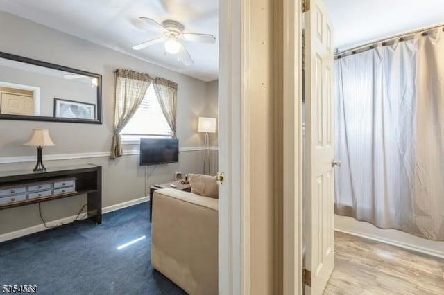 living area featuring baseboards and ceiling fan
