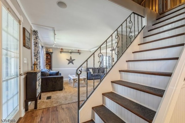staircase with track lighting and wood finished floors