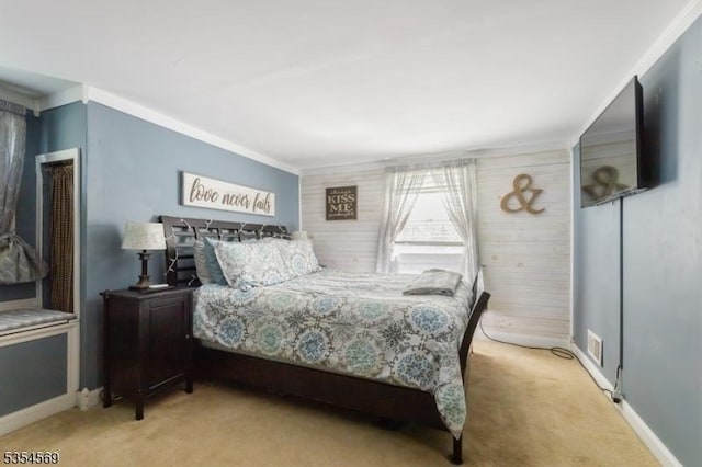 carpeted bedroom with crown molding, wood walls, and baseboards