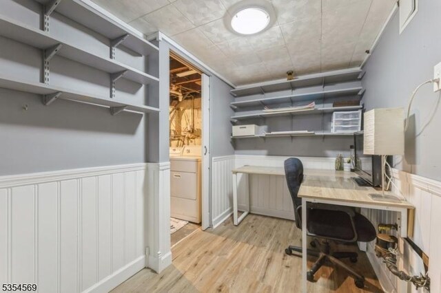 office with washer / dryer, a wainscoted wall, and light wood-type flooring