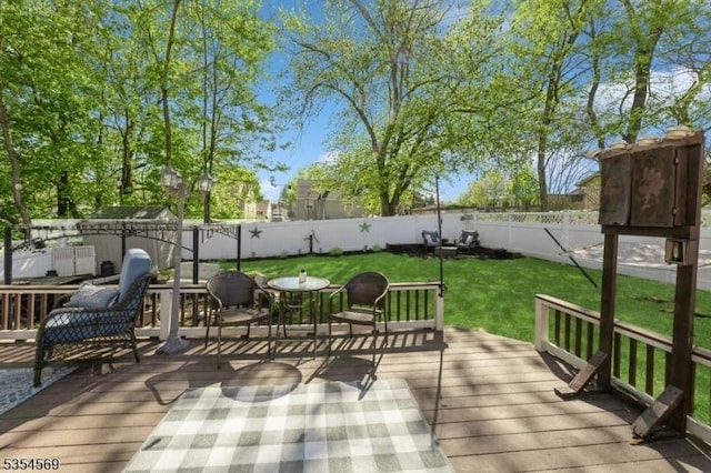 wooden terrace featuring a lawn and a fenced backyard