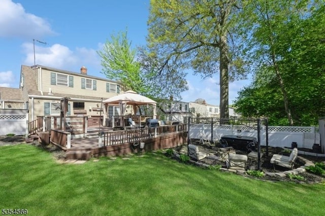 rear view of property with a lawn, a gazebo, a chimney, and a wooden deck