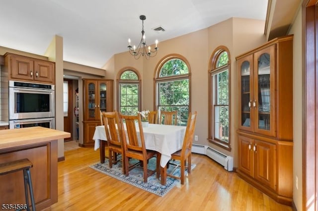 dining room with light wood-type flooring, a baseboard heating unit, a notable chandelier, and visible vents