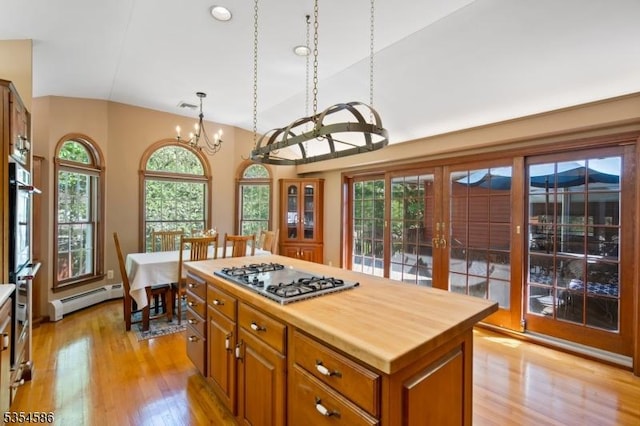 kitchen with an inviting chandelier, light wood-style floors, brown cabinets, french doors, and stainless steel gas stovetop