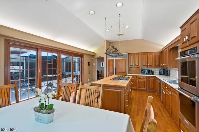 kitchen featuring wooden counters, appliances with stainless steel finishes, a center island, light wood finished floors, and lofted ceiling