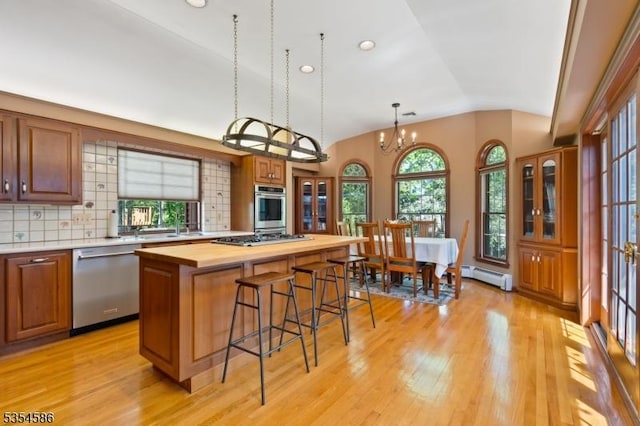 kitchen featuring light wood-style floors, a baseboard radiator, appliances with stainless steel finishes, and lofted ceiling