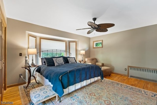bedroom with radiator, baseboards, and light wood-type flooring