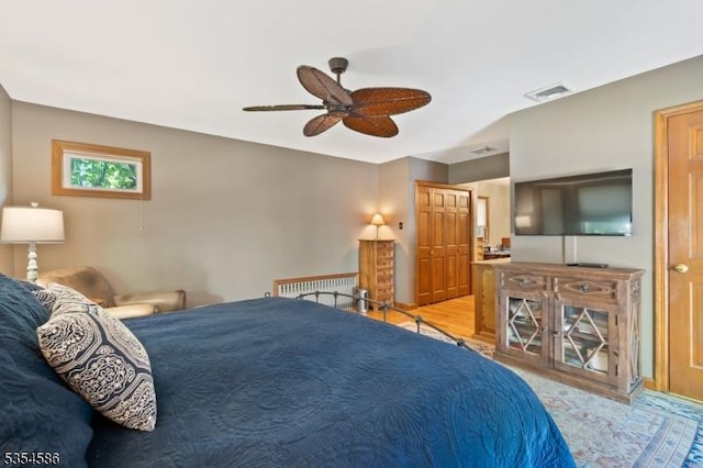 bedroom with ceiling fan, wood finished floors, and visible vents