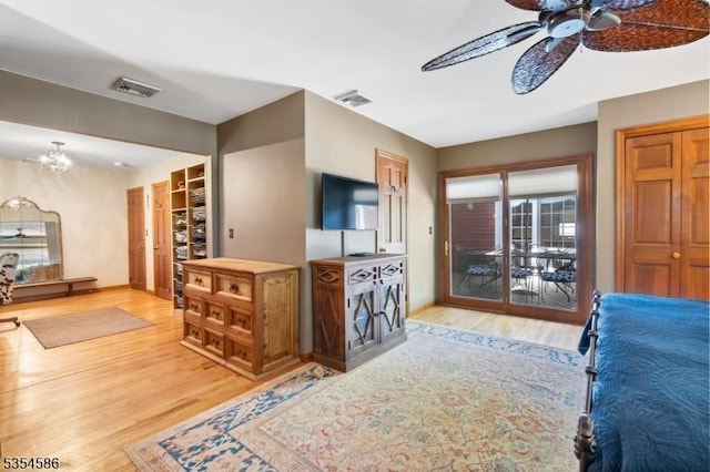living room with light wood-type flooring, ceiling fan with notable chandelier, and visible vents