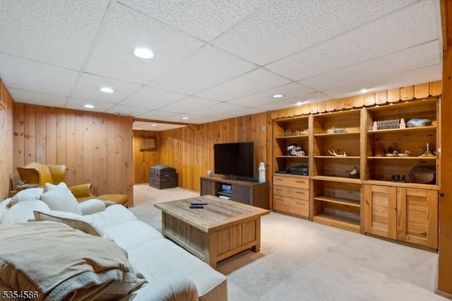 living room featuring wooden walls, a drop ceiling, recessed lighting, and light colored carpet