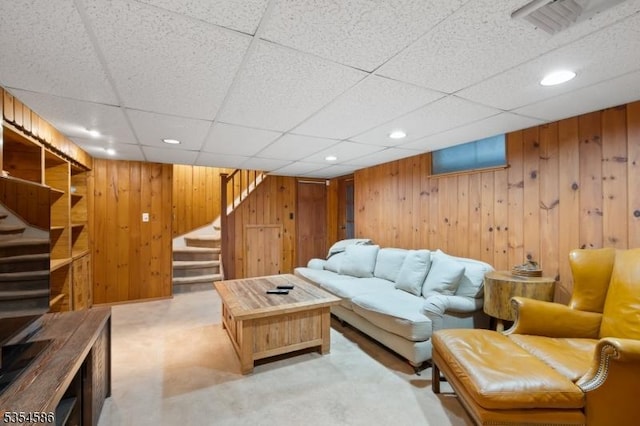 carpeted living room featuring recessed lighting, wood walls, a paneled ceiling, and stairway