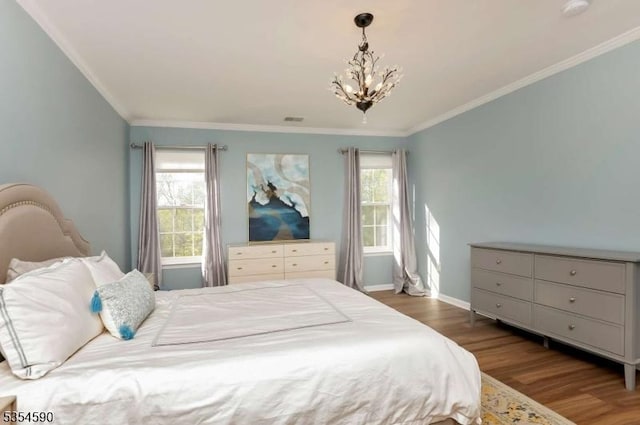 bedroom featuring visible vents, crown molding, wood finished floors, and a notable chandelier