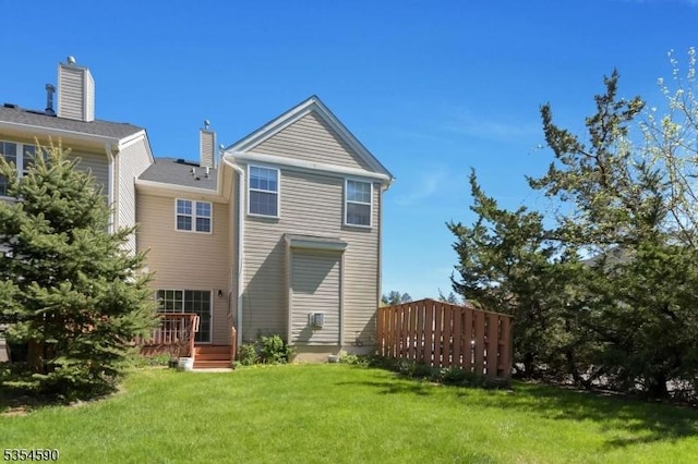 back of house featuring a lawn and a wooden deck