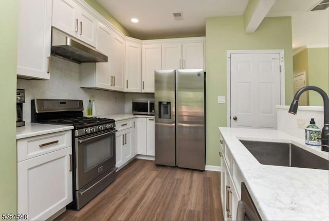 kitchen featuring visible vents, under cabinet range hood, a sink, dark wood finished floors, and appliances with stainless steel finishes