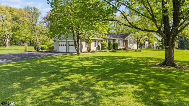 ranch-style house featuring an attached garage, a front lawn, and aphalt driveway