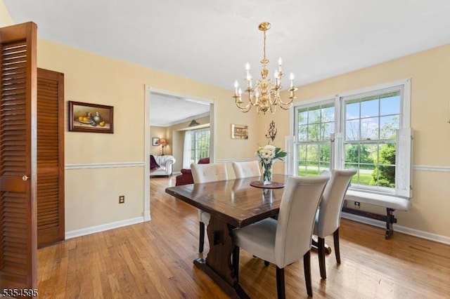 dining room featuring an inviting chandelier, baseboards, light wood-style flooring, and a wealth of natural light