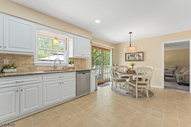 kitchen with stainless steel dishwasher, decorative backsplash, white cabinets, light stone counters, and a sink