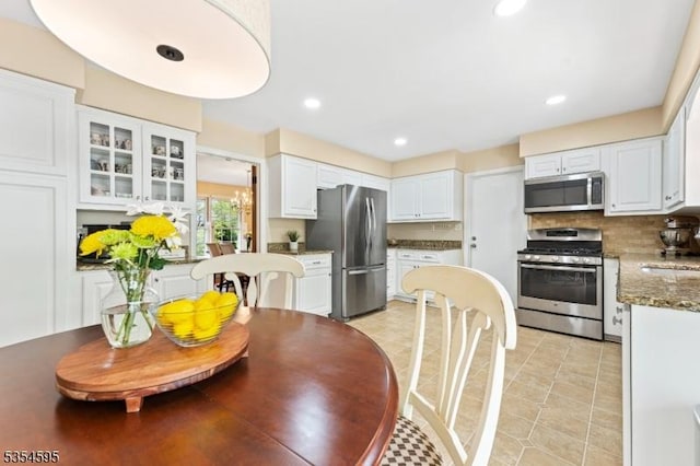 kitchen featuring appliances with stainless steel finishes, tasteful backsplash, white cabinets, glass insert cabinets, and recessed lighting