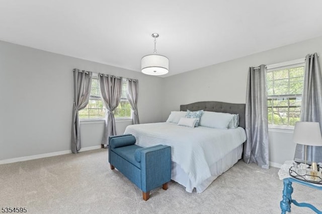 bedroom with baseboards, multiple windows, and light carpet