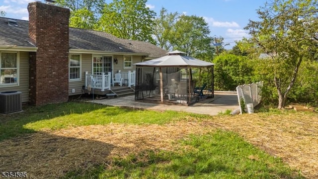 back of property featuring a gazebo, a chimney, central air condition unit, a patio, and a yard