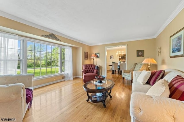 living room featuring baseboards, an inviting chandelier, ornamental molding, and light wood-style floors