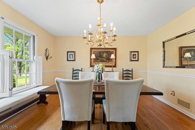 dining room featuring an inviting chandelier, plenty of natural light, wood finished floors, and visible vents