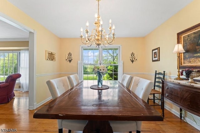 dining room with baseboards, a chandelier, a wealth of natural light, and wood finished floors