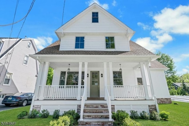 view of front of home featuring roof with shingles, a porch, and a front yard