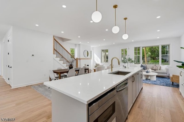 kitchen featuring a sink, open floor plan, stainless steel appliances, light wood-style floors, and recessed lighting